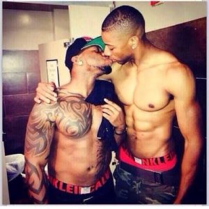 2 shirtless afro American Males kissing.