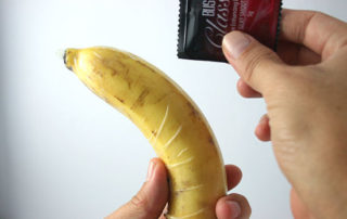 someone holding a banana with a condom over it demonstrating usage