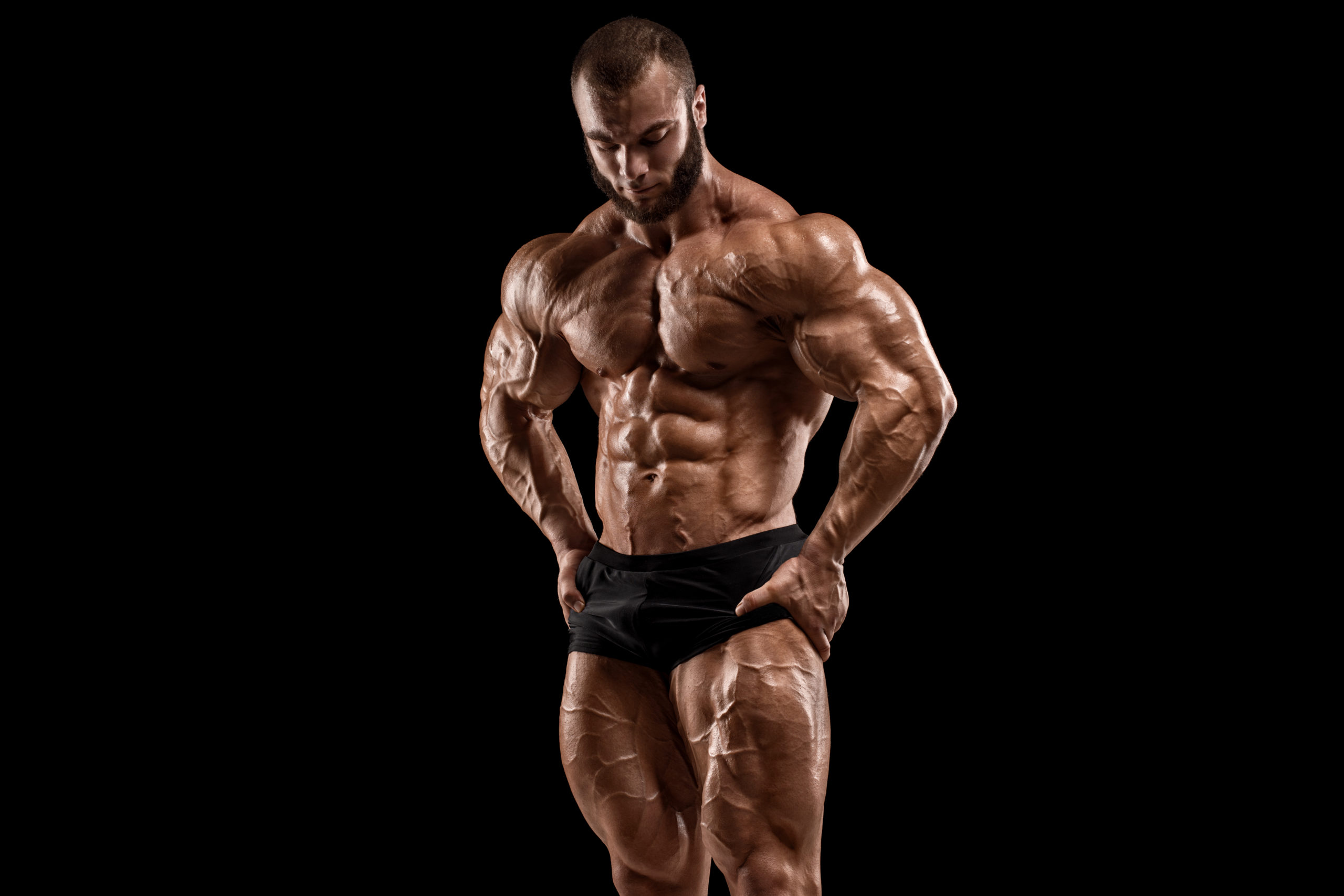 Bodybuilder man isolated on the black background. Strong male naked torso abs